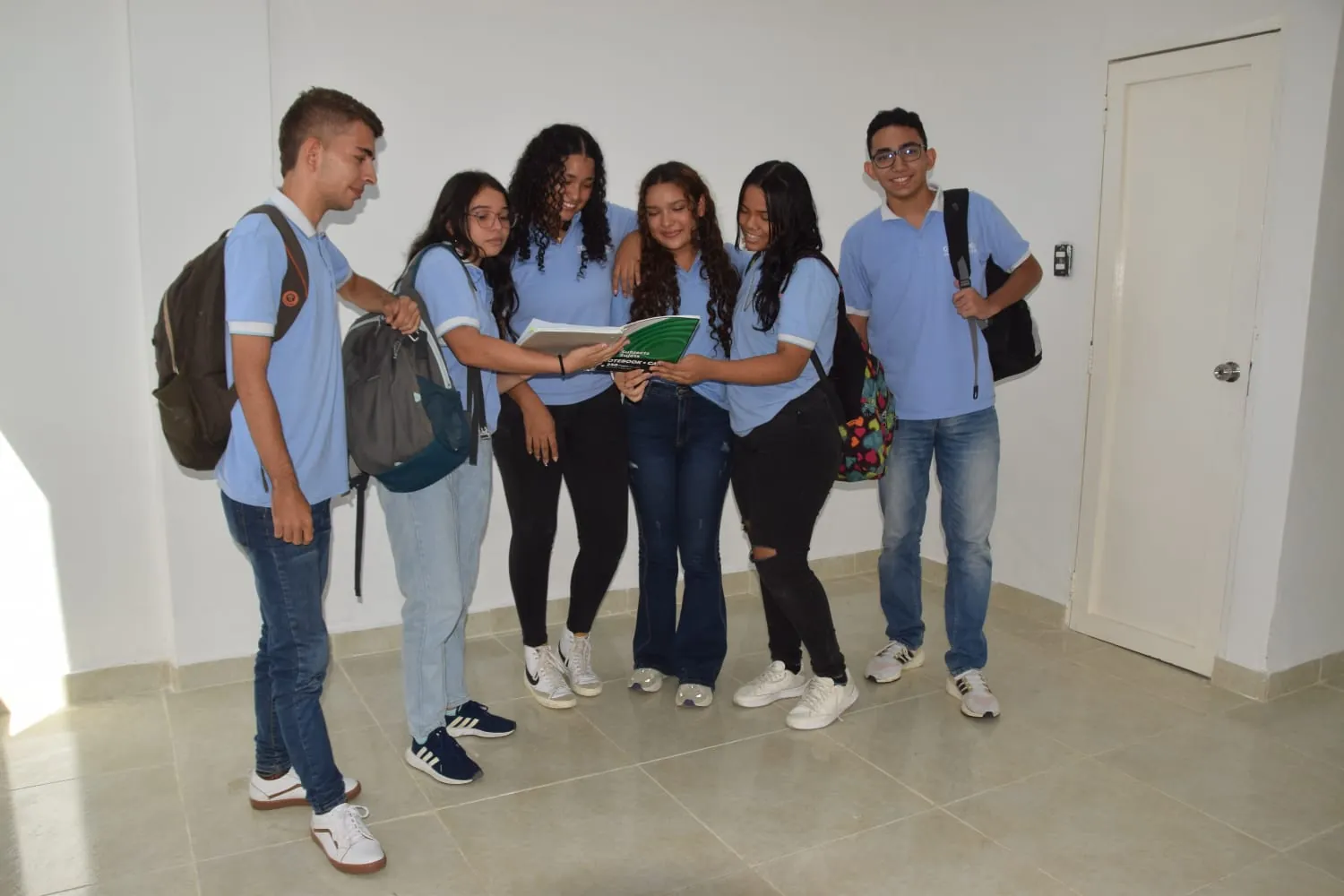 Seis estudiantes de CEPRODENT con el uniforme institucional consultan un cuaderno en la sede de Montería