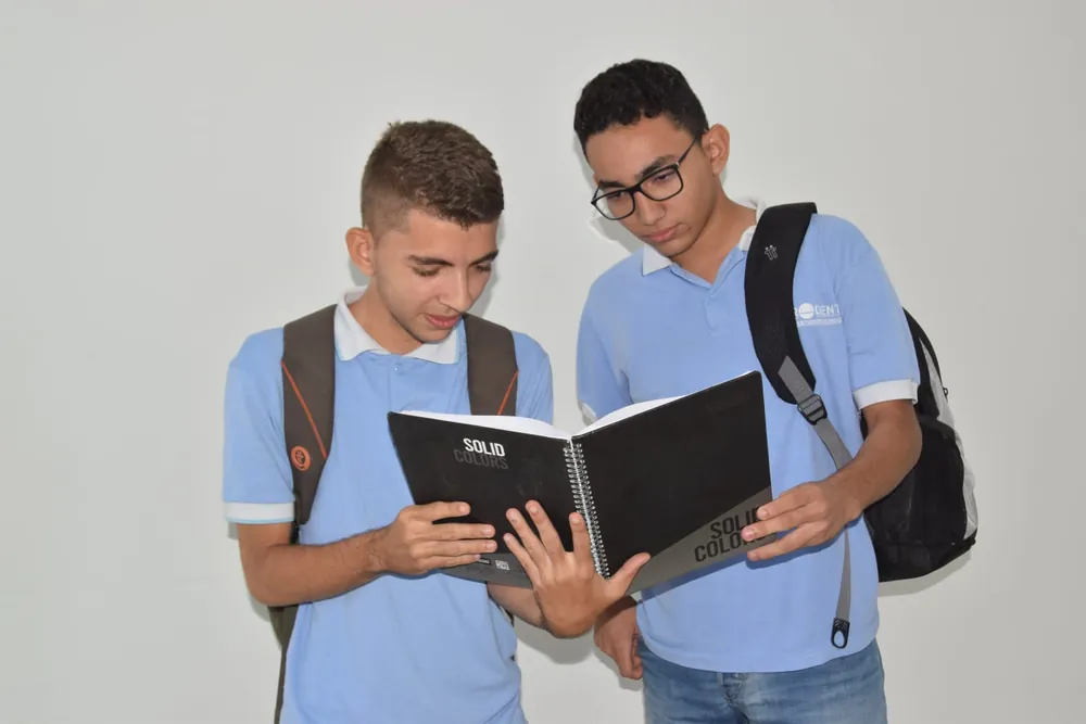 Dos estudiantes de CEPRODENT consultan un cuaderno con el uniforme institucional